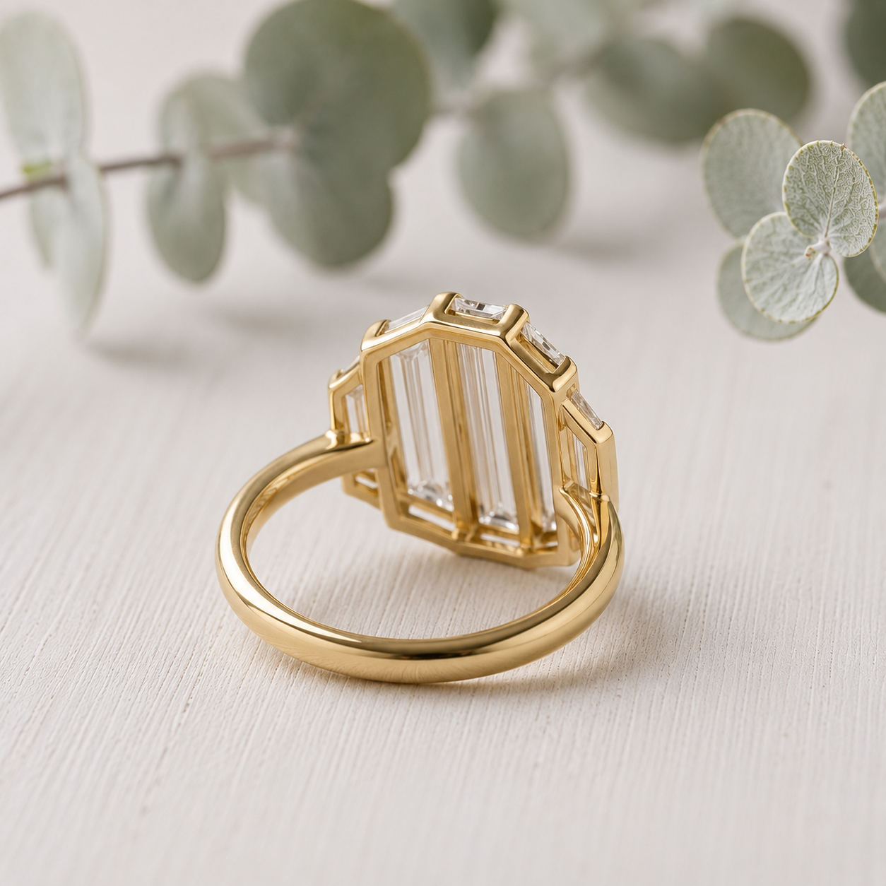 Baguette Diamond Engagement Ring featuring a lab-grown baguette cut diamond center stone with trapeze cut side diamonds in a geometric contemporary gold setting with a slim 1.7 mm band, designed as a modern minimalist engagement ring.