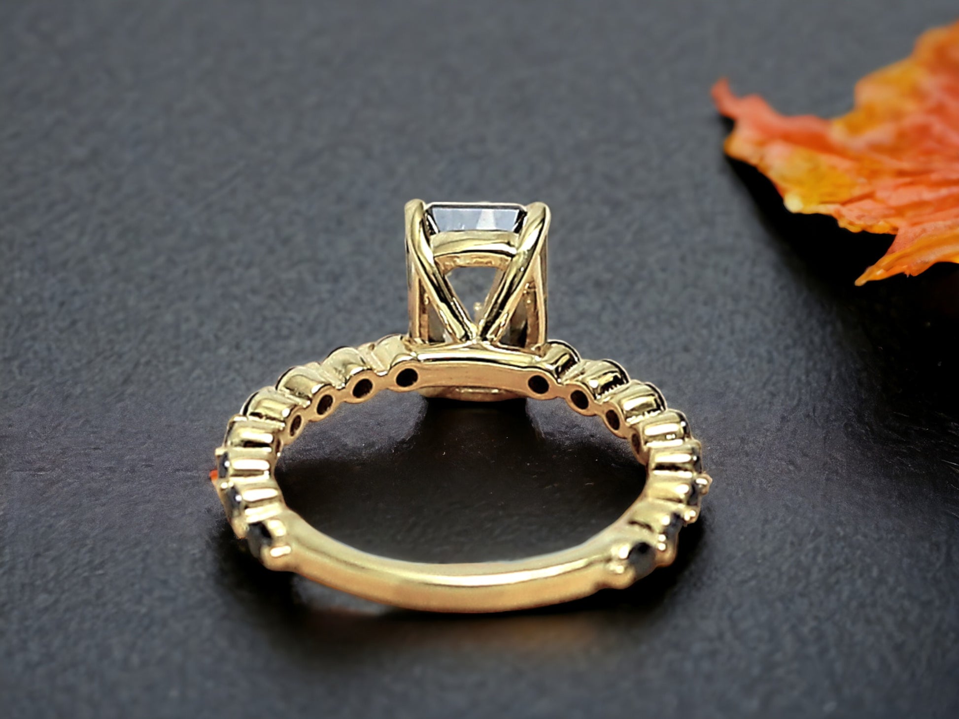 Emerald Cut Salt and Pepper Diamond Ring featuring a 2.58 CT natural salt and pepper diamond with speckled galaxy-like inclusions in a minimalist bezel setting, accented by 16 round brilliant diamonds in a straight 1.80 mm band for a modern geometric design.