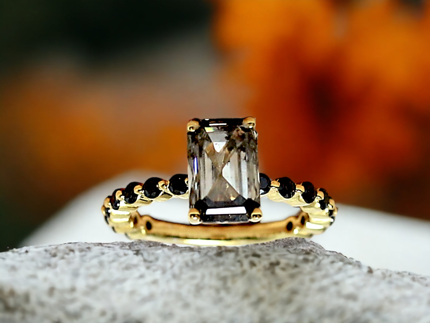 Emerald Cut Salt and Pepper Diamond Ring featuring a 2.58 CT natural salt and pepper diamond with speckled galaxy-like inclusions in a minimalist bezel setting, accented by 16 round brilliant diamonds in a straight 1.80 mm band for a modern geometric design.