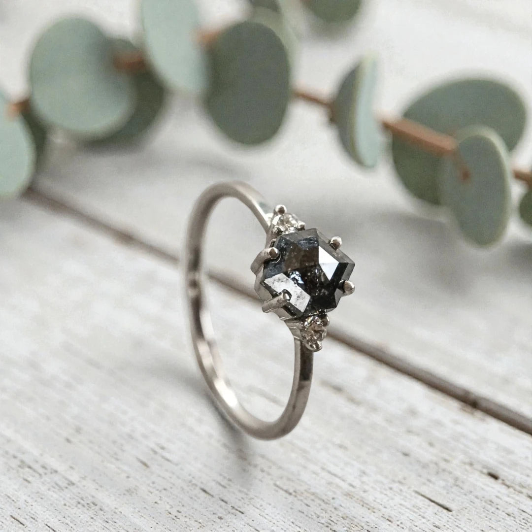 Hexagon diamond ring featuring a raw salt and pepper diamond center stone with natural organic inclusions, set in a handcrafted minimalist design with a clean modern band and geometric alternative engagement style.
