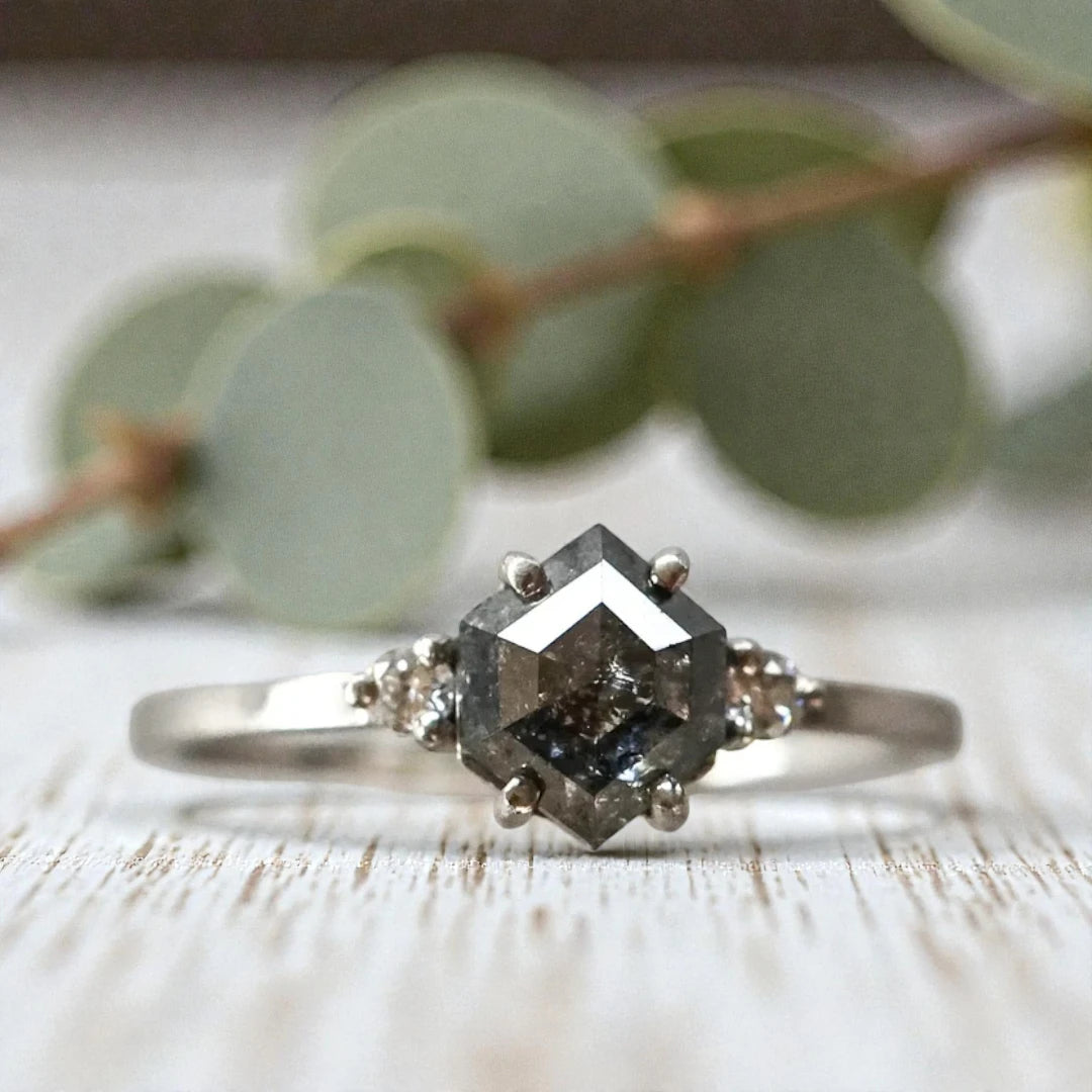 Hexagon diamond ring featuring a raw salt and pepper diamond center stone with natural organic inclusions, set in a handcrafted minimalist design with a clean modern band and geometric alternative engagement style.